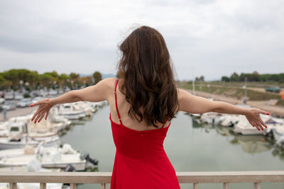 Rear view of woman with arms outstretched standing against sky