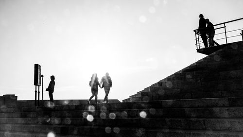 People walking on staircase against sky