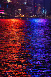 Reflection of illuminated bridge over river against sky at night