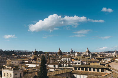 Buildings in town against cloudy sky