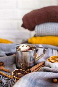 Close-up of mulled wine with cinnamons and orange fruits on fabric