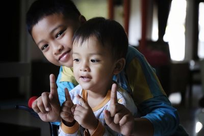 Portrait of cute boy with brother gesturing at home