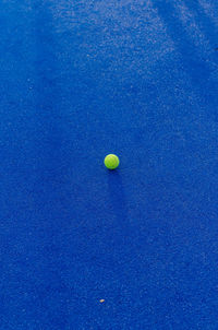 An isolated ball on a blue paddle tennis court. racket sports concept
