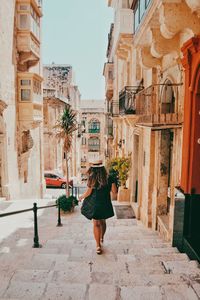 Rear view of woman walking on street amidst buildings