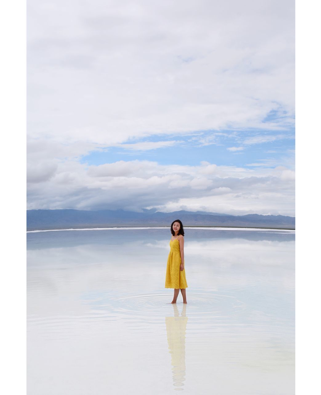 WOMAN STANDING IN SEA AGAINST SKY