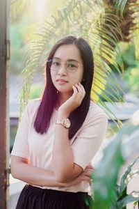 Portrait of young woman standing against plants