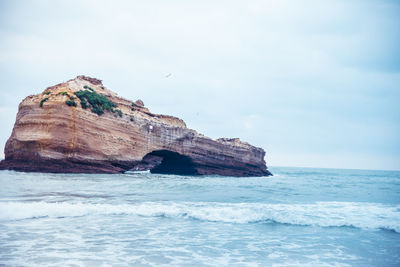 Rock formation in sea against sky