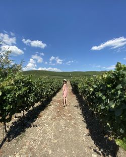 Woman walking on dirt road against sky