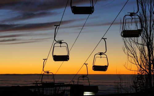 Low angle view of overhead cable car against sky during sunset