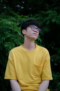 Portrait of young man standing against plants