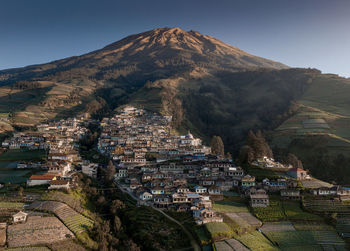 Aerial view of town by mountains against clear sky