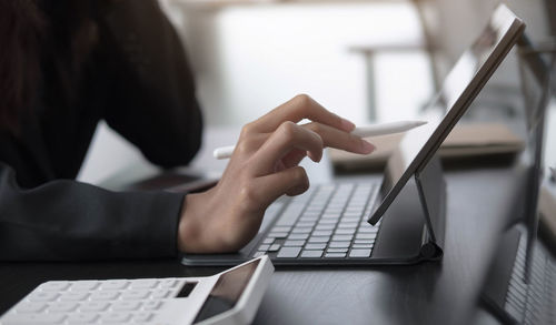 Midsection of woman using mobile phone on table