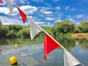 Red flag by lake against sky