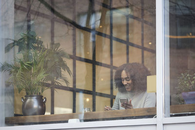 Young woman using cell phone in cafe