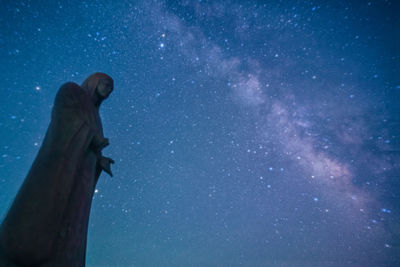 Low angle view of person standing against blue sky at night