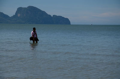 Rear view of woman standing on cliff by sea