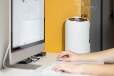 White air humidifier spreading steam up. humidification of dry air while man working on computer.