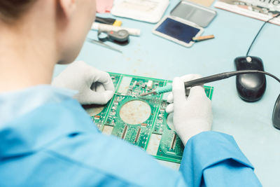 High angle view of woman holding work tool over table