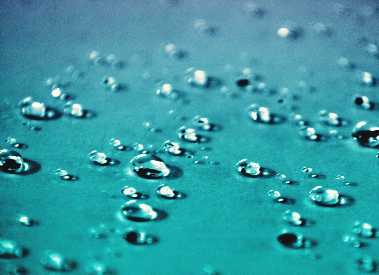 CLOSE-UP OF WATER DROPS ON BLUE SURFACE