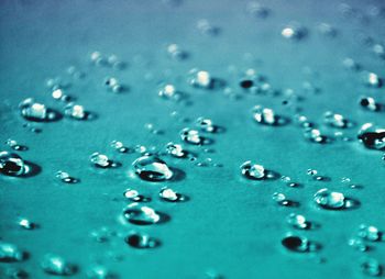 Close-up of raindrops on blue water