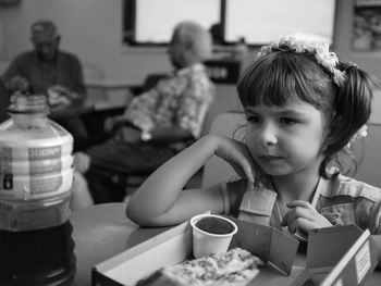 Close-up of girl holding drink while sitting on table