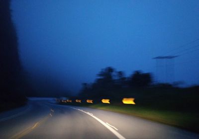 Cars on road against blue sky at night