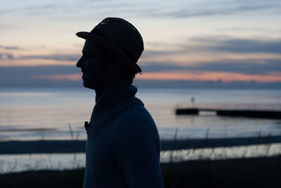 Close-up of man standing at beach during sunset