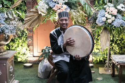 Man playing musical instrument by plants in yard