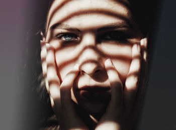 Close-up portrait of young woman with hands on chin