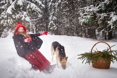 Portrait of woman with dog on snow covered field