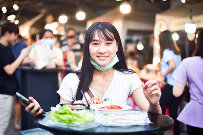 Portrait of a smiling young woman eating food at restaurant