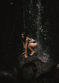 Portrait of shirtless young woman on rock