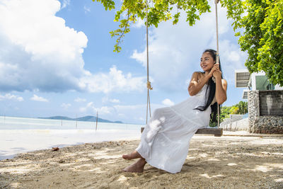 Beautiful woman sitting on a swing at the beach in phuket