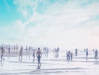 Group of people on snowy field against sky