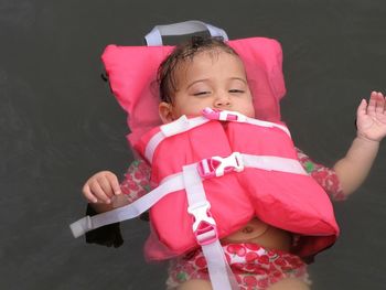 High angle view of baby girl with life jacket floating in lake