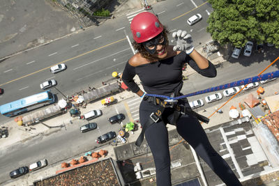 A woman wearing a hero costume with protective helmet walking down a tall rappel building. 