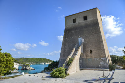 Low angle view of building by river against blue sky