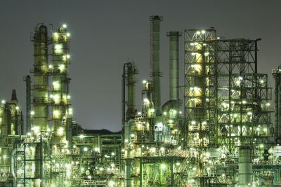 Illuminated factory against sky at night