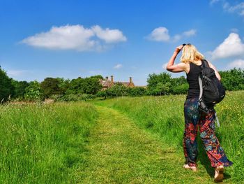 Rear view of woman walking on grassy footpath