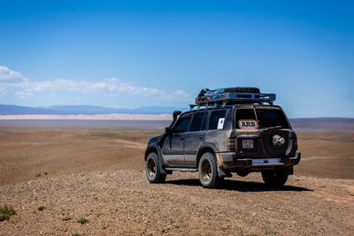 Vintage car on land against blue sky