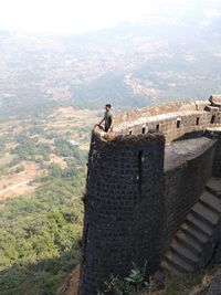 Young man standing on fort overlooking landscape