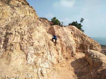 Rear view of person on rock formations against sky