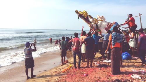 Group of people immersing ganesha statue in sea