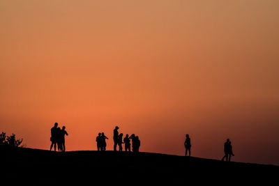 Silhouette of people against orange sky