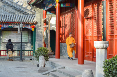 Rear view of people walking on street by building