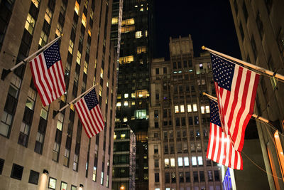 Low angle view of american flags on buildings at night