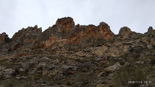 Low angle view of rocky mountain against sky