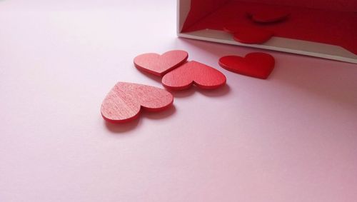 Close-up of box with red heart shapes over pink background