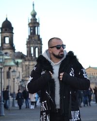Young man standing against building in city during winter