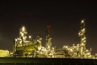 Illuminated factory against sky at night